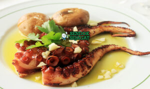 Polvo à Lagareiro khas Portugal siap saji: gurita potong empuk renyah keemasan di loyang, kentang kecil panggang, bawang putih memarkan, minyak zaitun menggenang, dan peterseli tabur, terlihat gurih hangat dengan uap mengepul