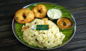 Mangkuk Ven Pongal khas India Selatan berisi bubur beras kacang hijau kental gurih, disiram ghee harum, taburan cashew goreng renyah dan daun kari segar, disajikan dengan sambar dan chutney
