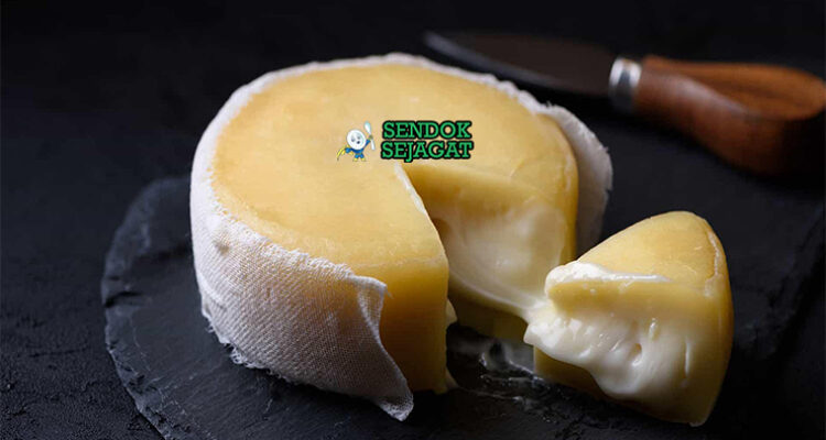 Queijo da Serra khas Portugal siap saji: keju domba lembut krimy berwarna putih krem, tekstur kental lumer, dipotong memperlihatkan bagian dalam halus, disajikan dengan roti gandum dan madu, terlihat gurih menggoda