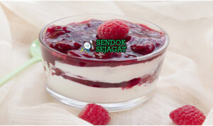 Mangkok Rote Grütze khas Jerman dengan pudding berry merah lembut, potongan buah utuh, dituang krim segar, tampak segar dan menggugah selera