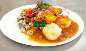 Sajta de Pollo khas Bolivia disajikan hangat dalam mangkuk dengan potongan ayam empuk, kuah pedas kuning dari ají amarillo, kentang, kacang polong, dan nasi putih