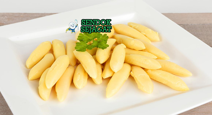 Piring schupfnudeln khas Austria berbentuk lonjong kecokelatan renyah, disiram mentega cokelat harum, taburan bawang goreng dan peterseli segar, disajikan hangat