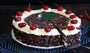 Potongan kue Schwarzwälder Kirschtorte khas Jerman menampilkan lapisan sponge cokelat lembut, whipped cream putih, filling ceri merah, dan taburan serutan cokelat gelap