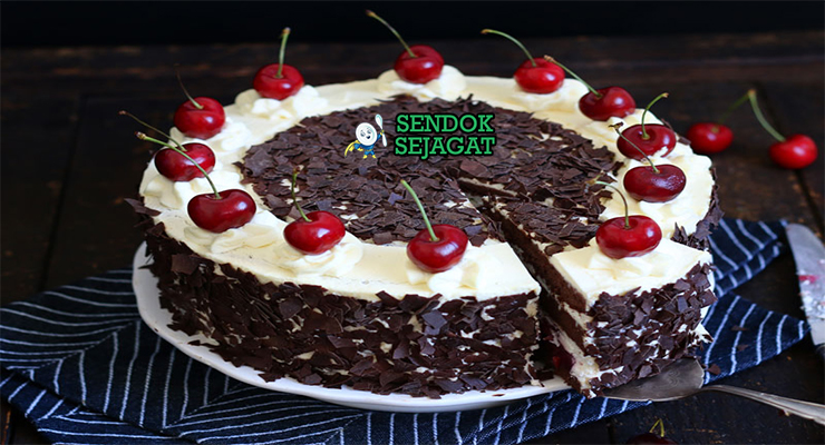 Potongan kue Schwarzwälder Kirschtorte khas Jerman menampilkan lapisan sponge cokelat lembut, whipped cream putih, filling ceri merah, dan taburan serutan cokelat gelap