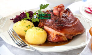 Schweinshaxe Siap Saji dengan Kulit Crispy Schweinshaxe khas Jerman dengan kulit renyah keemasan menggelembung, daging empuk di bawahnya, disajikan dengan sauerkraut dan bir, tampak gurih dan menggugah selera