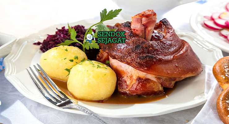 Schweinshaxe khas Jerman dengan kulit renyah keemasan menggelembung, daging empuk di bawahnya, disajikan dengan sauerkraut dan bir, tampak gurih dan menggugah selera