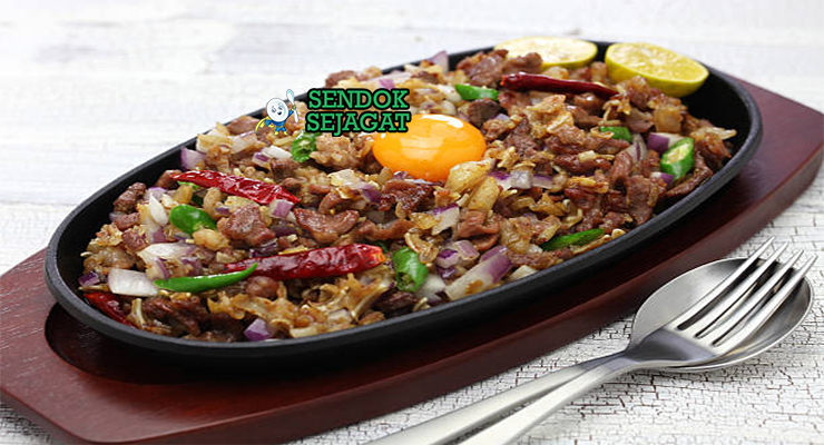 Sizzling pork sisig khas Filipina siap saji: daging babi cincang renyah di hot plate besi panas, bawang bombay segar, cabai rawit merah, jeruk nipis peras, uap mengepul dan bunyi sizzling menggoda