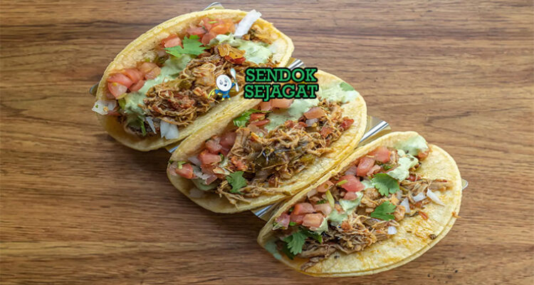 Tinga de pollo khas Meksiko siap saji: ayam suwir empuk dalam saus tomat merah pedas chipotle, bawang bombay karamel, disajikan dengan tortilla jagung hangat, alpukat iris, krim asam, keju cotija, dan jeruk nipis, terlihat gurih menggoda