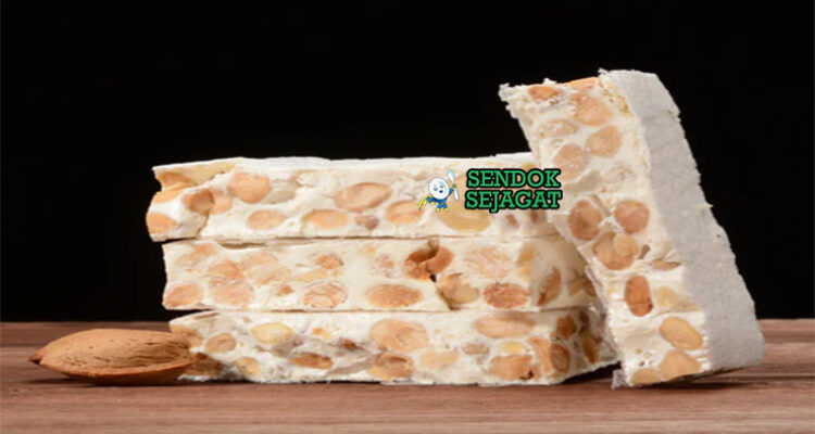 Turrón khas Spanyol siap saji: blok nougat keras Alicante dengan almond utuh terlihat renyah, madu mengkilap, potong kotak di piring kayu, terasa manis dan crunchy