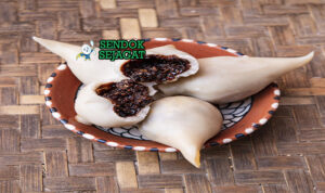 Yomari Siap Saji Hangat dengan Isian Manis Yomari khas Nepal berbentuk bulan sabit dengan kulit tepung beras lembut, isian gula kelapa meleleh, tampak manis harum menggugah selera