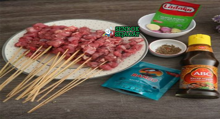 Bahan-bahan resep Sate Kerbau termasuk daging kerbau, bawang, cabai, kecap manis, lengkuas, serai, dan daun jeruk siap dibakar