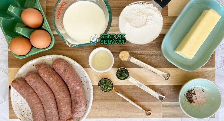 Bahan-bahan resep Toad in the Hole termasuk sosis babi, tepung terigu, telur, susu, minyak, dan bawang bombay siap dipanggang