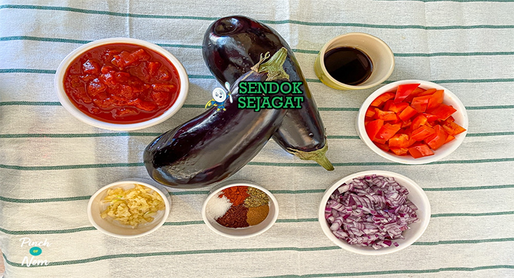 Bahan-bahan resep Imam bayildi termasuk terong ungu, bawang bombay, tomat, bawang putih, minyak zaitun, dan rempah siap dipanggang