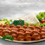 Çiğ Köfte khas Turki dengan adonan bulgur halus merah, dibungkus daun selada, tomat, bawang, saus nar eksis, tampak segar pedas menggugah selera