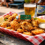 Abalone goreng tepung bir khas Australia dengan lapisan crispy keemasan, disiram saus sweet sour, daun ketumbar garnish, sajian hangat di piring putih