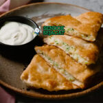 Bolani khas Afghanistan berbentuk setengah bulan renyah, isi kentang daun bawang gurih, tampak hangat menggugah selera