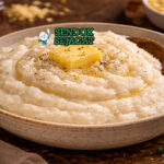 Mieliepap khas Afrika Selatan disajikan hangat di piring putih dengan saus tomat pedas dan daging panggang di sampingnya