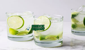 Caipirinha khas Brasil di gelas tinggi dengan es batu banyak, potongan jeruk nipis segar, tampak menyegarkan manis asam menggugah selera