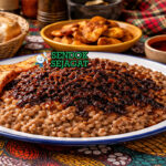 Ewa Agoyin khas Nigeria dengan kacang hitam mata yang ditumbuk lembut disiram saus Agoyin pedas gelap dari minyak kelapa sawit, disajikan hangat di piring dengan roti agege