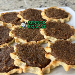 Gizzada khas Jamaika berbentuk setengah bulan renyah, isi kelapa parut manis gurih mengalir, tampak manis tropis menggugah selera