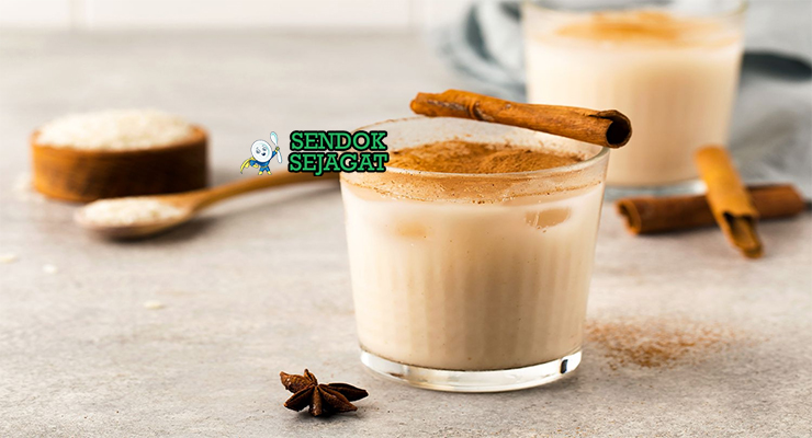 Horchata khas Meksiko berwarna putih susu segar di gelas tinggi dengan es batu, taburan kayu manis, tampak menyegarkan manis wangi