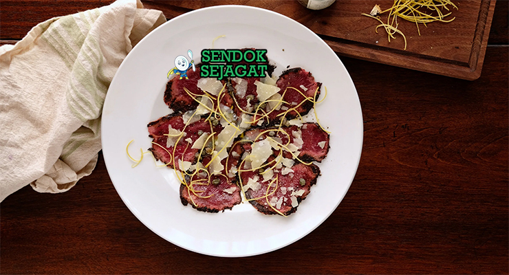Kangaroo Carpaccio khas Australia dengan irisan daging kanguru mentah tipis merah muda, black garlic umami, minyak zaitun, tampak segar gurih menggugah selera