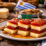 Martin Fierro khas Uruguay dengan irisan keju Manchego asin bertumpuk pasta quince manis, taburan walnut, disajikan cantik di piring putih untuk dessert elegan