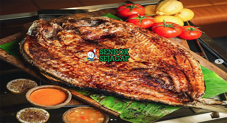 Masgouf khas Irak dengan ikan mas panggang terbuka renyah kecokelatan, asap kayu bakar, tampak gurih hangat menggugah selera