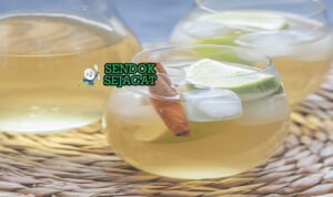 Mauby khas Karibia berwarna cokelat kemerahan segar di gelas dengan es batu dan irisan jeruk nipis, tampak menyegarkan manis gurih