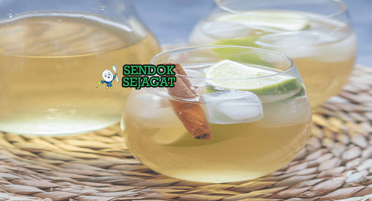 Mauby khas Karibia berwarna cokelat kemerahan segar di gelas dengan es batu dan irisan jeruk nipis, tampak menyegarkan manis gurih