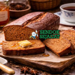 Pain d'Épices khas Prancis dengan roti cokelat keemasan beraroma rempah kayu manis dan jahe, dipotong tebal di piring putih