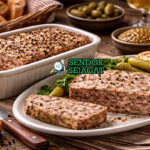 Pâté de Campagne khas Prancis dengan terin daging kasar berwarna cokelat keemasan, diiris tebal di piring putih bersama roti baguette dan cornichon