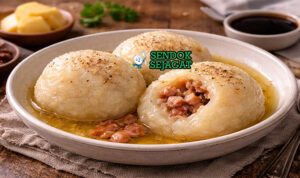 Poutine Râpée khas Kanada dengan dumpling kentang parut lembut, isi daging babi gurih, disiram mentega, tampak hangat menggugah selera