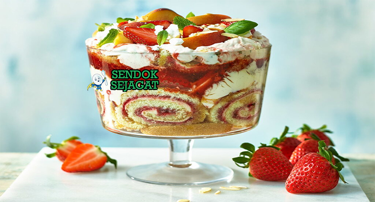 Trifle khas Inggris di mangkuk kaca transparan dengan lapisan sponge cake, custard vanila, buah segar berwarna-warni, whipped cream, tampak manis segar menggugah selera