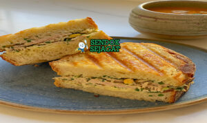 Tuna Melt khas Amerika dengan roti panggang renyah, isian tuna mayo creamy, keju cheddar leleh meluber, tampak gurih hangat menggugah selera