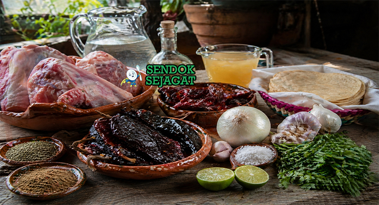 Kaki babi, cabai guajillo kering, bawang putih, bawang bombay, jintan, oregano, cuka, dan kaldu tersusun rapi sebagai bahan chamorros de cerdo