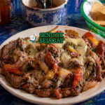 Hidangan alambre berisi potongan daging sapi, paprika merah hijau, bawang, dan keju leleh dengan warna cerah dan tekstur juicy