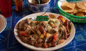 Hidangan alambre berisi potongan daging sapi, paprika merah hijau, bawang, dan keju leleh dengan warna cerah dan tekstur juicy