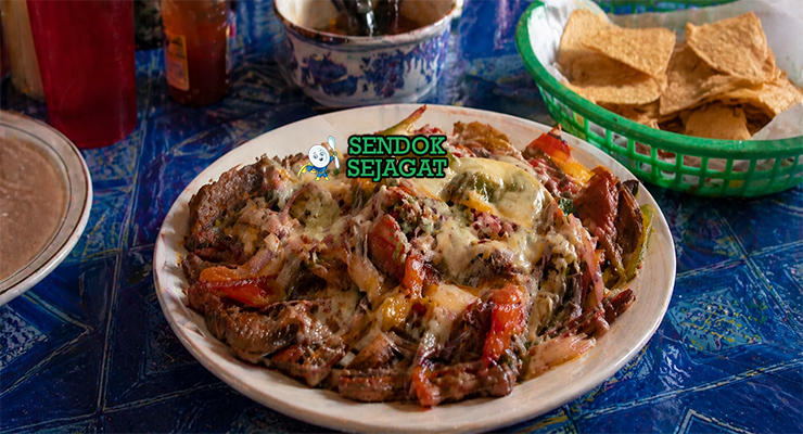 Hidangan alambre berisi potongan daging sapi, paprika merah hijau, bawang, dan keju leleh dengan warna cerah dan tekstur juicy