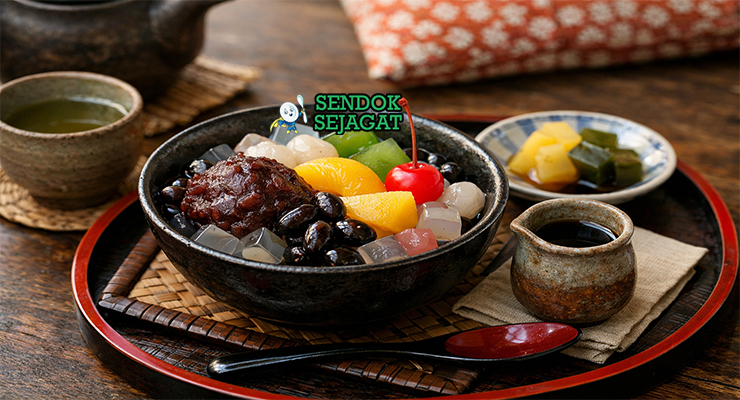 Anmitsu khas Jepang dengan kubus agar-agar kenyal, pasta kacang merah, ceri segar, kiwi, mandarin, dan sirup hitam disajikan di mangkuk kaca dengan es batu