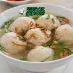 Bakso ikan putih kenyal dalam kuah bening dengan taburan daun bawang dan bawang goreng