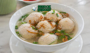 Bakso ikan putih kenyal dalam kuah bening dengan taburan daun bawang dan bawang goreng