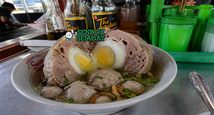 Semangkuk bakso telur khas Tasikmalaya dengan kuah bening, bakso besar berisi telur kuning di tengah, taburan daun bawang dan bawang goreng, tampilan hangat dan menggugah selera