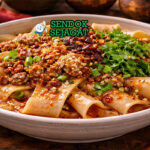 Biang biang noodles khas Tiongkok disajikan hangat di mangkuk keramik dengan taburan daun bawang, biji wijen, dan minyak cabai yang mengkilap