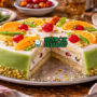 Irisan cassata siciliana Italia autentik dengan lapisan marzipan hijau cerah, filling ricotta creamy berisi cokelat dan buah manis, hiasan buah kristal di piring putih yang memukau