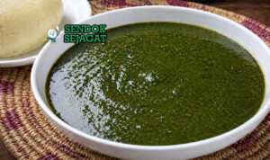 Ewedu soup berwarna hijau dengan tekstur lembut dan sedikit kental, disajikan dalam mangkuk bersama amala khas Nigeria