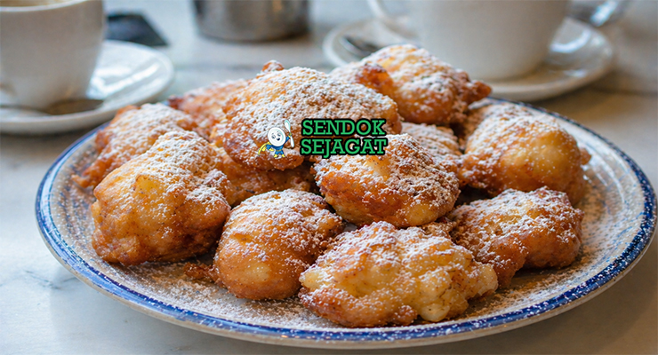 Bola-bola frittelle berwarna keemasan dengan taburan gula halus, tekstur renyah luar dan lembut di dalam