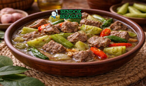 Hidangan garang asem daging sapi Jawa Tengah autentik dengan potongan daging empuk juicy, kuah santan bening asam segar, irisan belimbing wuluh dan cabe rawit di mangkuk tanah liat yang menggugah selera