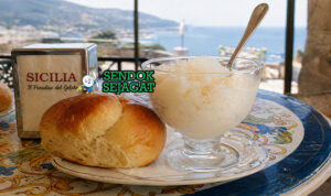 Granita khas Sisilia dalam gelas dengan kristal es halus rasa almond dan lemon, disajikan bersama brioche lembut berwarna keemasan di meja kafe Italia