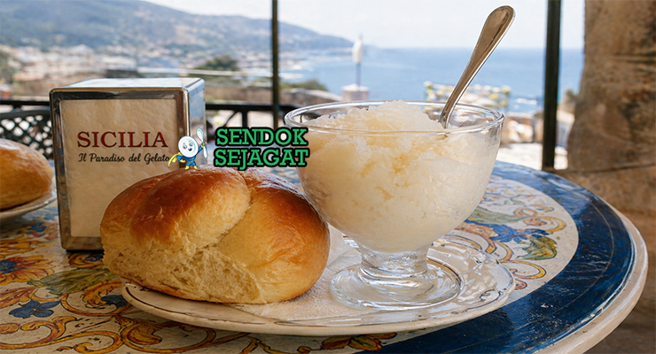 Granita khas Sisilia dalam gelas dengan kristal es halus rasa almond dan lemon, disajikan bersama brioche lembut berwarna keemasan di meja kafe Italia